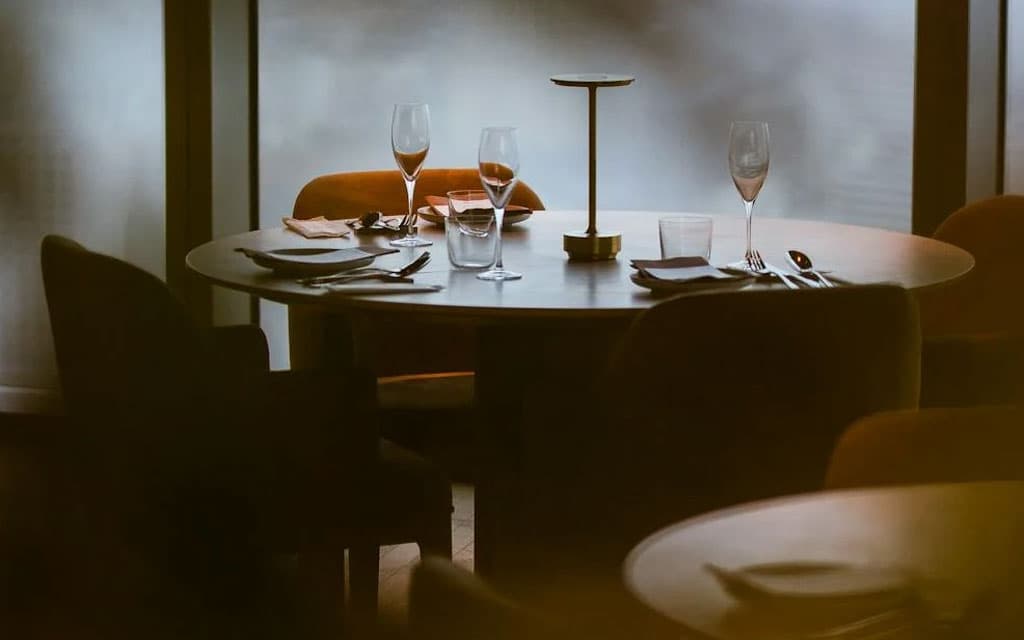 A dimly lit table set with glassware and utensils in a chic restaurant.